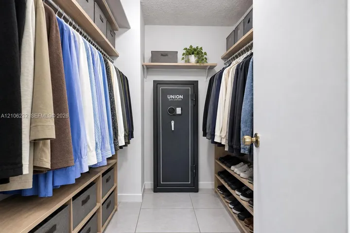 Walk-in closet featuring multi-level wooden hanging rods, integrated wooden shelving, built-in lower drawers, and tile flooring