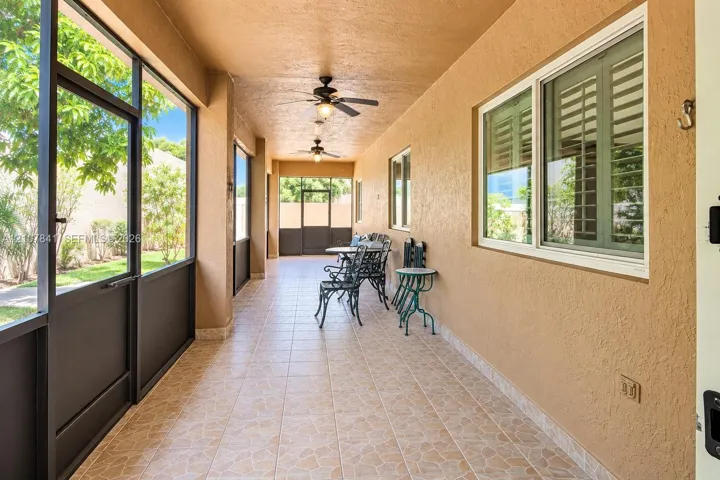 Screened-in covered patio featuring tile flooring, ceiling fans, and installed window shutters