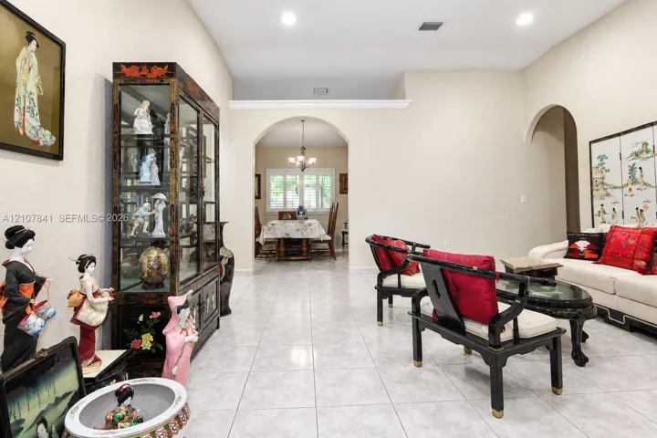 Open-concept interior featuring neutral-toned walls, high ceilings with recessed lighting, light-colored tile flooring, and prominent arched architectural detailing