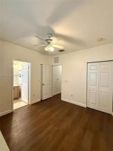 Interior space featuring wood-finish flooring, white paneled doors, ceiling fan with integrated lighting, and dual-door closet storage