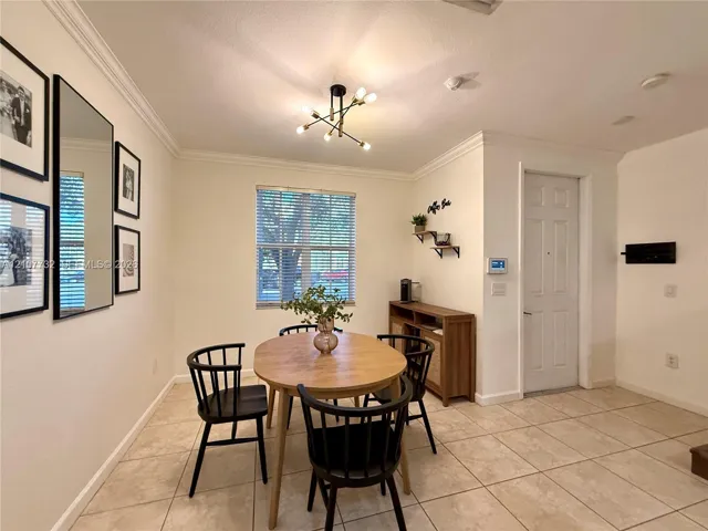 Neutral-toned tile flooring, crown molding, multi-arm geometric light fixture, and single-panel interior door