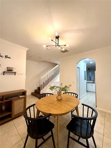 Tile flooring, crown molding, multi-arm chandelier, and arched doorway
