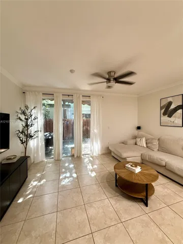 Large-format neutral floor tile, ceiling fan, and sliding glass door with external patio access