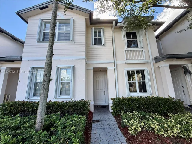 Two-story exterior featuring a mix of horizontal lap siding and textured stucco finish, a covered entryway, decorative upper-level balcony railing, and a stone-paver walkway