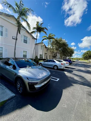 Multi-story stucco exterior with white shutters, exterior lighting fixtures, and mature palm tree landscaping