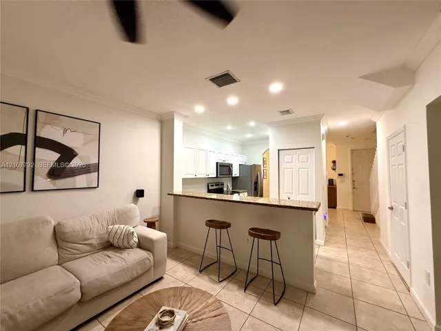 Kitchen featuring white cabinetry, a stone-surfaced breakfast bar, and recessed lighting