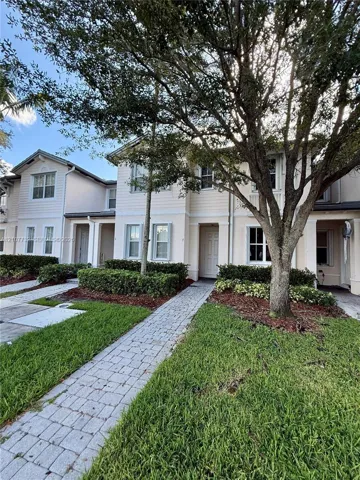 Two-story exterior featuring lap siding, paver walkways, manicured landscaping, and mature canopy trees
