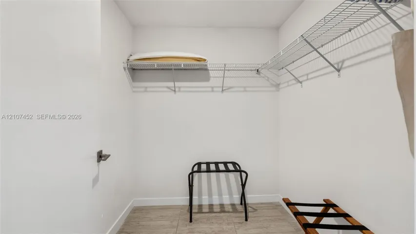 Walk-in storage space featuring wire shelving and stone-finish tile flooring