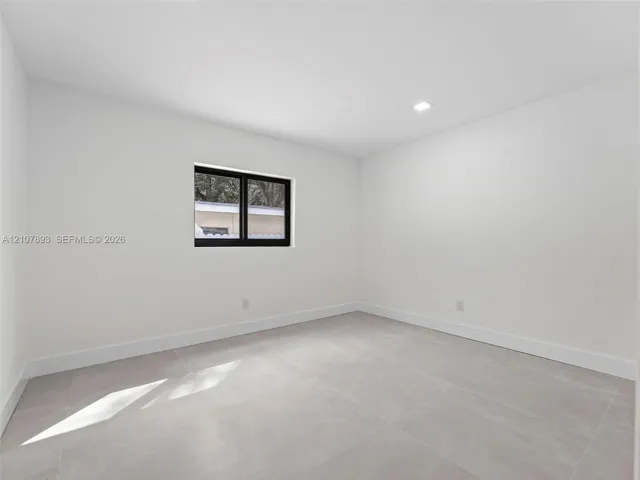 Neutral-toned tile flooring, recessed ceiling lighting, and a single-pane window with a black frame