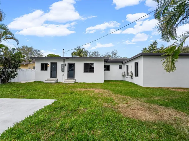 Exterior featuring a white stucco facade, flat roofline, dark-framed windows, and a paved concrete patio area