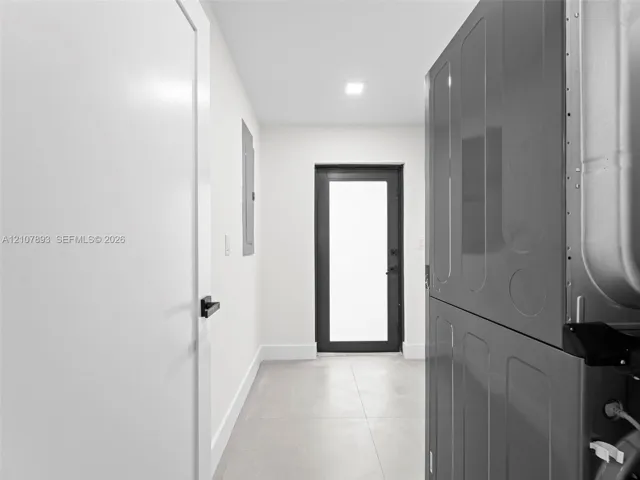 Neutral-toned tiled flooring, modern glass-panel exterior door, and matte black hardware