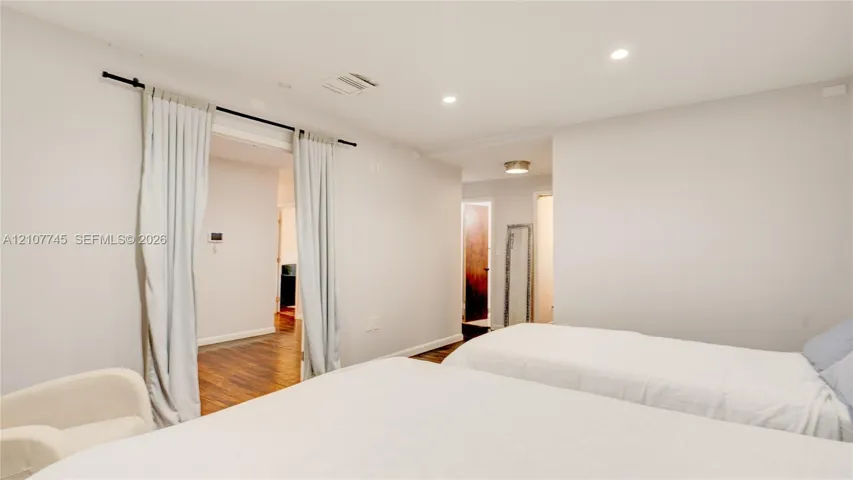 Neutral interior space featuring recessed ceiling lighting, wood-finish flooring, and a sliding curtain partition