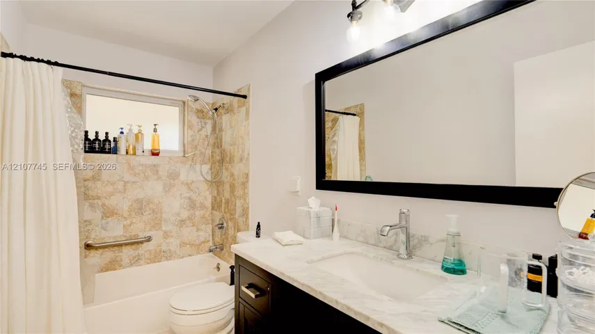 Bathroom featuring a vanity with a light-toned stone countertop, integrated sink, and dark cabinetry