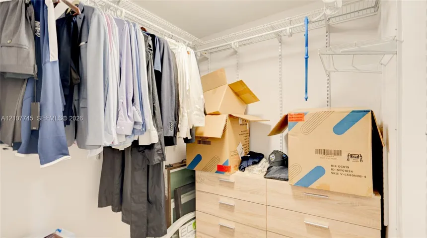 Walk-in closet featuring white wire shelving and built-in light-tone wood-finish drawer cabinetry