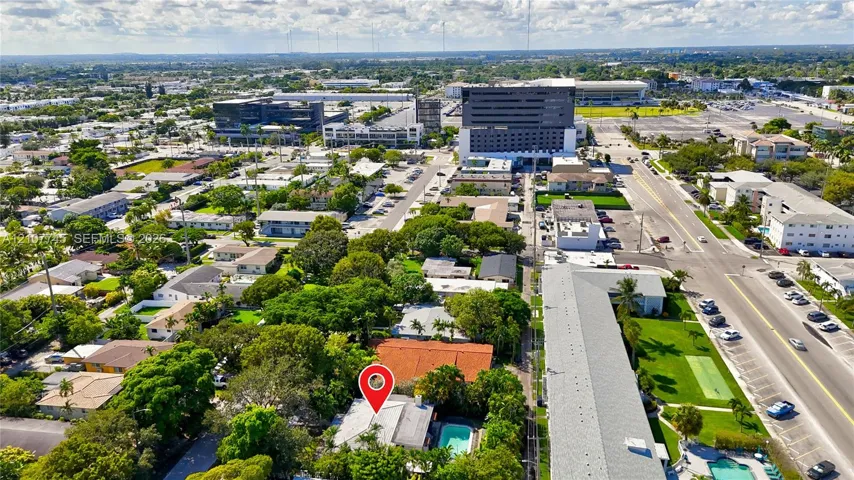 Aerial perspective featuring a residential property with a tile roof, an in-ground swimming pool, and mature perimeter landscaping
