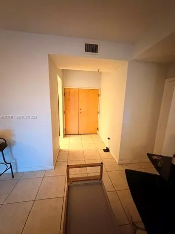 Entryway featuring double wood-finish doors and neutral tile flooring