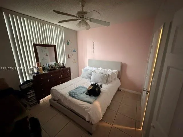 Bedroom featuring ceramic tile flooring, vertical window blinds, and a ceiling fan with integrated lighting