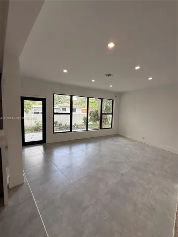 Open-concept interior featuring large-format tile flooring, recessed lighting, and expansive windows with black frames