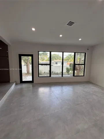 Large format tile flooring, recessed lighting, and expansive black-framed windows featuring integrated door access