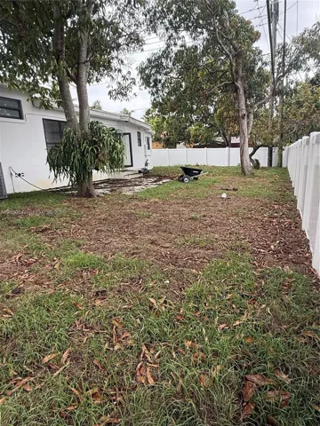 Backyard featuring a paved patio area, mature trees, and a perimeter vinyl privacy fence