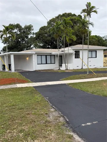 Single-story residence featuring a painted masonry exterior, a covered carport, a tile roof, and black-framed windows