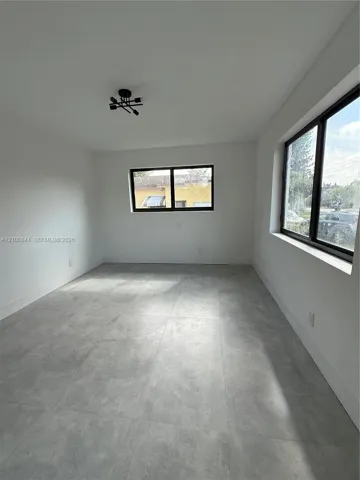 Neutral-toned large-format tile flooring, matte black window frames, and geometric multi-light flush-mount fixture
