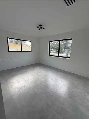 Large-format tile flooring, dual windows with dark frames, and a geometric multi-arm ceiling fixture