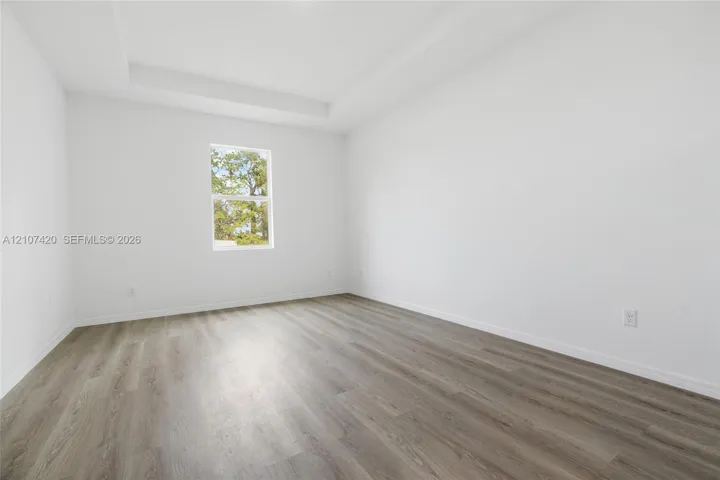 Interior room featuring a tray ceiling, neutral wall tones, and wood-finish flooring