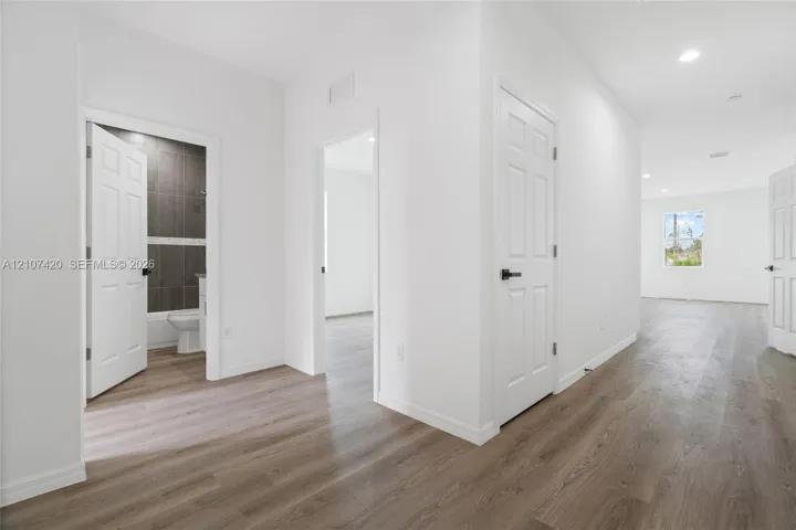 Interior space featuring wood-finish flooring, recessed lighting, and multi-panel interior doors with matte black hardware