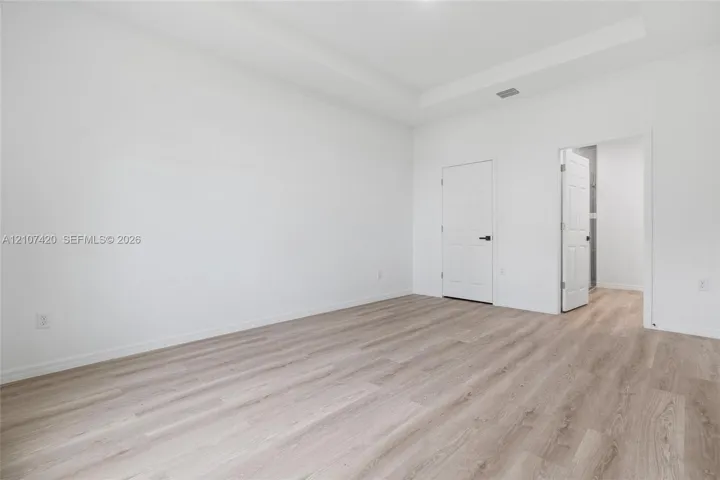 Interior space featuring a tray ceiling, neutral wall tones, and wood-finish flooring