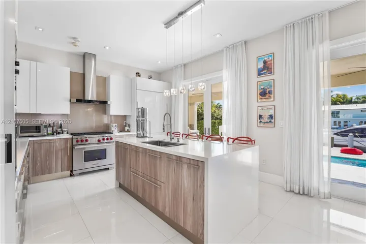 Kitchen featuring a central island with a solid-surface countertop, high-gloss white and wood-finish cabinetry, stainless steel professional-grade range with matching range hood, and polished tile flooring