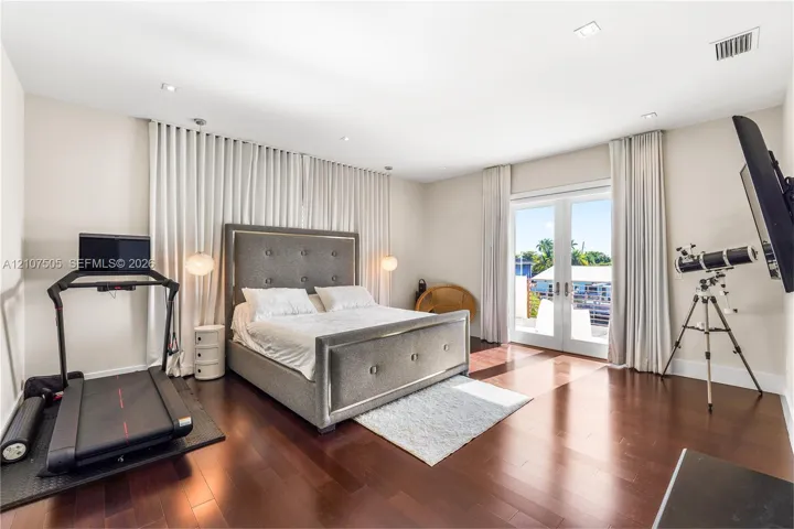 Spacious room featuring dark-toned wood-finish flooring, recessed lighting, and full-height wall drapery