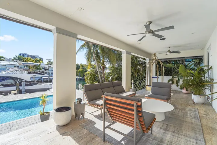 Covered patio featuring stone tile flooring, recessed lighting, ceiling fans, and structural support columns