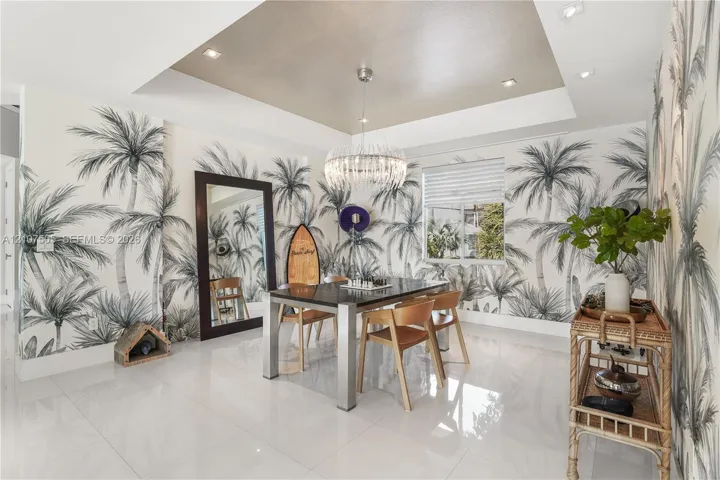 Tray ceiling featuring recessed lighting and a central tiered crystal chandelier, complemented by large-format polished tile flooring