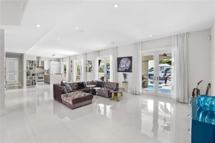 Open-concept interior featuring large-format polished tile flooring, recessed lighting, built-in shelving, and dual sets of glass-paned doors