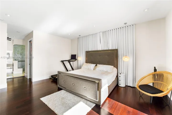 Spacious room featuring dark wood-finish flooring, recessed lighting, and wall-to-wall pleated window treatments