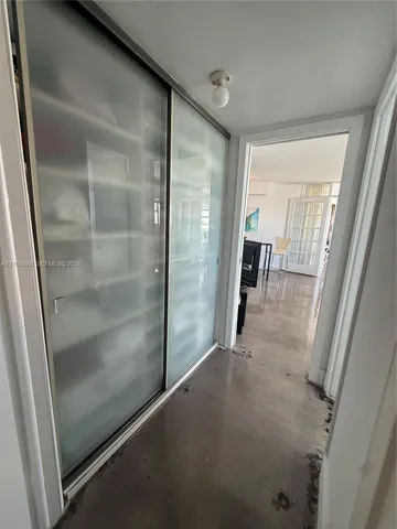 Sliding closet doors with frosted glass panels, polished concrete flooring, and flush-mount ceiling light fixture