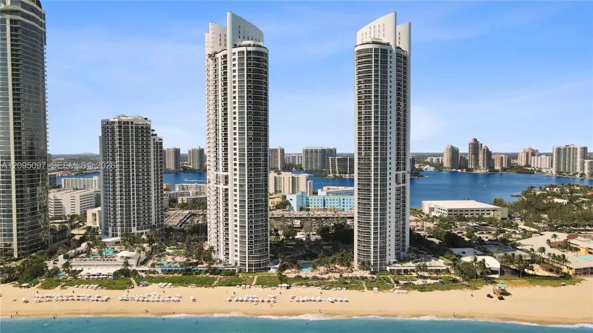 High-rise residential towers featuring glass-curtain facades, deep-set private balconies, and direct beachfront access with immediate proximity to coastal waterways