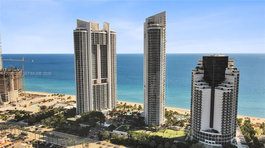 High-rise residential architecture featuring floor-to-ceiling glass, extensive wrap-around balconies, direct oceanfront positioning, and coastal shoreline access
