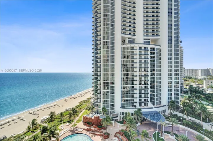 High-rise residential tower featuring floor-to-ceiling glass windows, wraparound balconies, an oceanfront location, a resort-style swimming pool, and a porte-cochère entry
