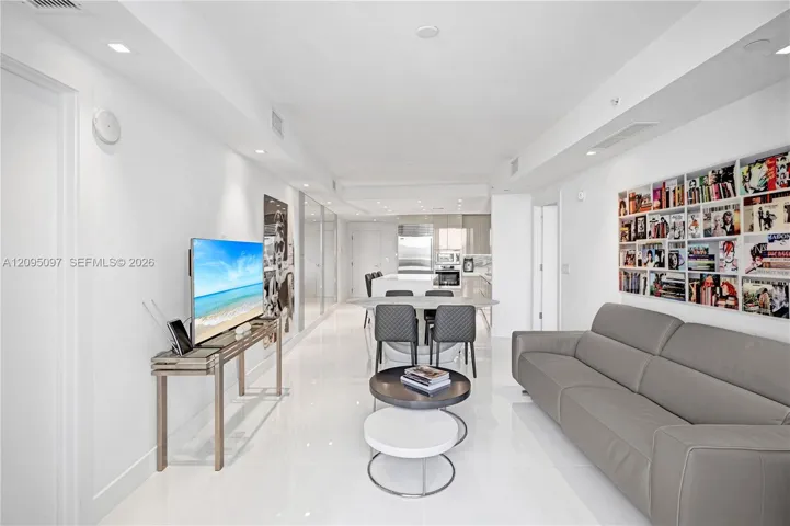 Open-concept interior featuring large-format polished tile flooring, recessed ceiling lighting, and custom built-in recessed shelving