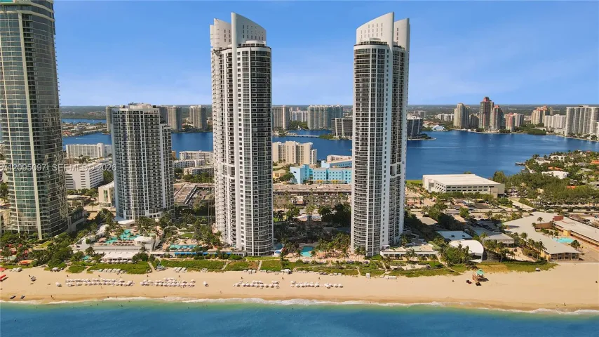 High-rise residential towers featuring glass-facade architecture, expansive balconies, direct waterfront access, and proximity to the coastline