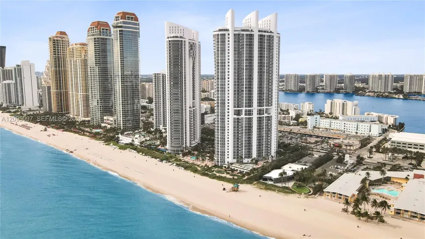 Coastal high-rise buildings situated directly on a sandy shoreline, featuring floor-to-ceiling glass facades and proximity to the Atlantic Ocean