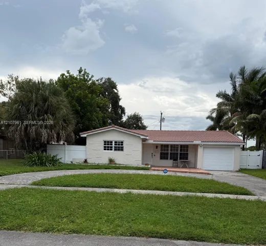 Single-story residence featuring a tile roof, stucco exterior, attached garage, and white vinyl privacy fencing