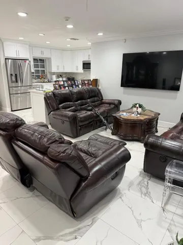 Open floor plan featuring white cabinetry, stone-finish tile flooring, recessed ceiling lighting, and stainless steel appliances