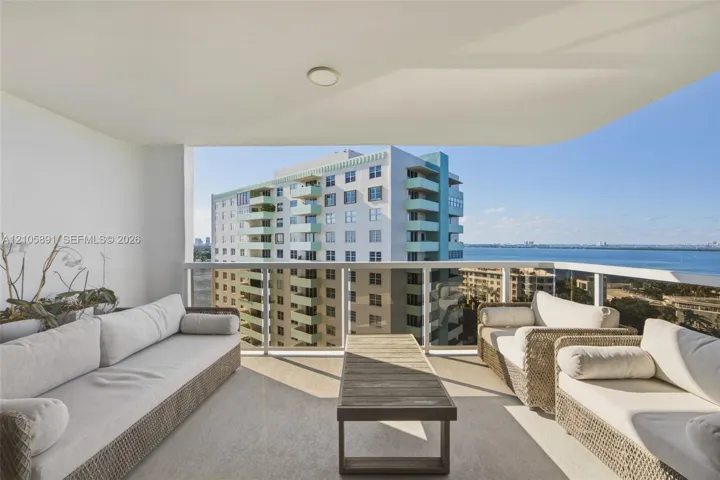 Covered balcony featuring a concrete floor, glass panel railing, and ceiling-mounted lighting