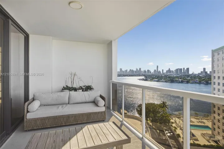 Covered balcony featuring white walls, concrete flooring, and a glass-panel railing with metallic framing