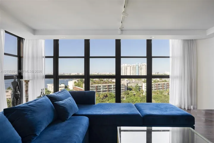 Floor-to-ceiling windows with dark-finish frames, wood-finish flooring, and track lighting