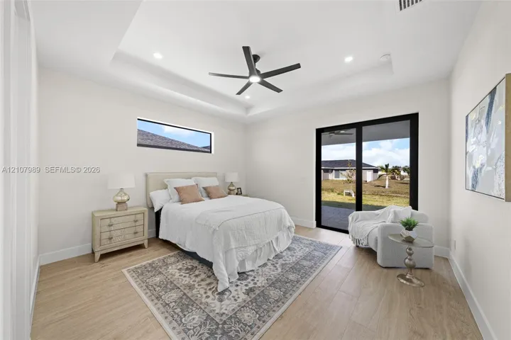 Tray ceiling with recessed lighting, wood-finish flooring, matte black ceiling fan, horizontal clerestory window, and black-framed sliding glass doors