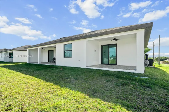 Exterior featuring a concrete block facade with a covered patio, recessed ceiling fans, glass sliding doors, and a shingle roof